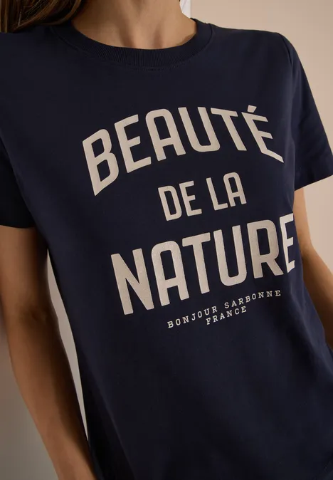 Frau trägt dunkelblaues T-Shirt mit weißem Aufdruck "Beauté de la Nature".