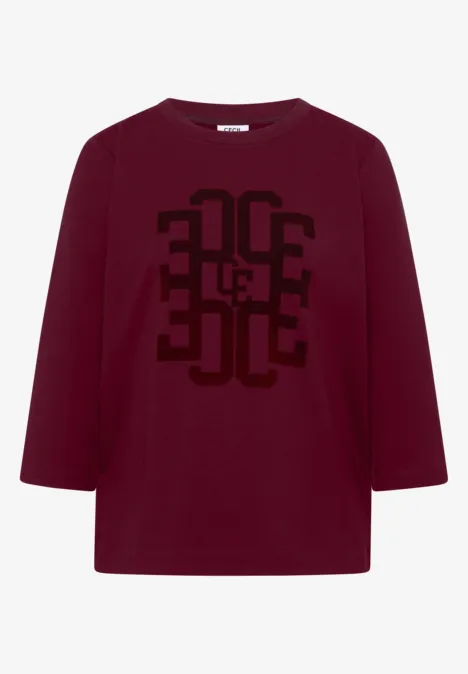 Dunkelrotes Langarmshirt mit schwarzem geometrischem Print auf der Vorderseite.