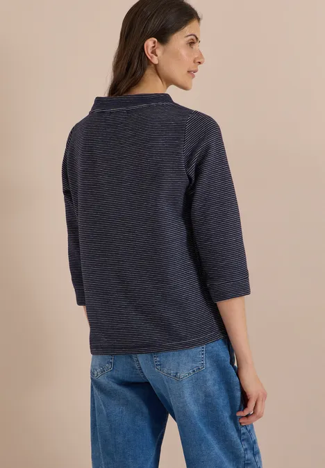 Ottoman Shirt im Two-Tone-Look urban dark blue Frau von hinten trägt dunkelblauen Pullover mit 3/4-Ärmeln und Jeans vor hellem Hintergrund.