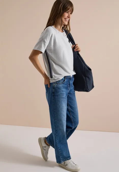 Shirt met aflopende schouders, ronde hals en band light grey melange Frau in weißem T-Shirt und weiten Jeans trägt eine blaue Tasche und weiße Sneaker vor hellem Hintergrund