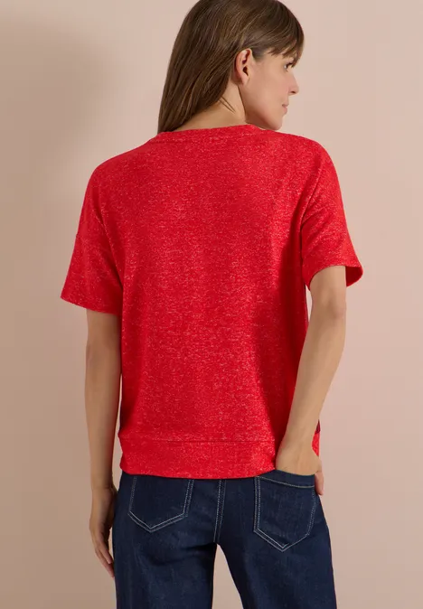 Shirt met verlaagde schouders, ronde hals en band flame red melange Frau von hinten in rotem Kurzarmshirt und blauen Jeans vor beigem Hintergrund.