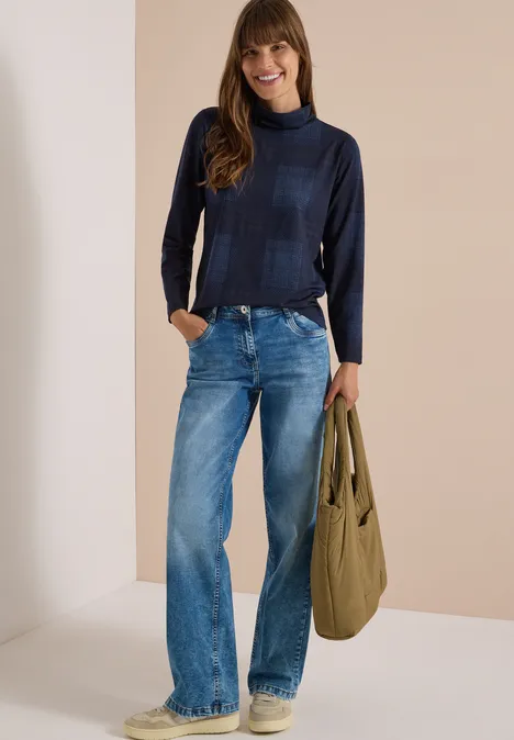 T-shirt à manches longues, col roulé et imprimé urban dark blue Femme en pull à col roulé bleu foncé, jean ample et sac kaki sur fond neutre.