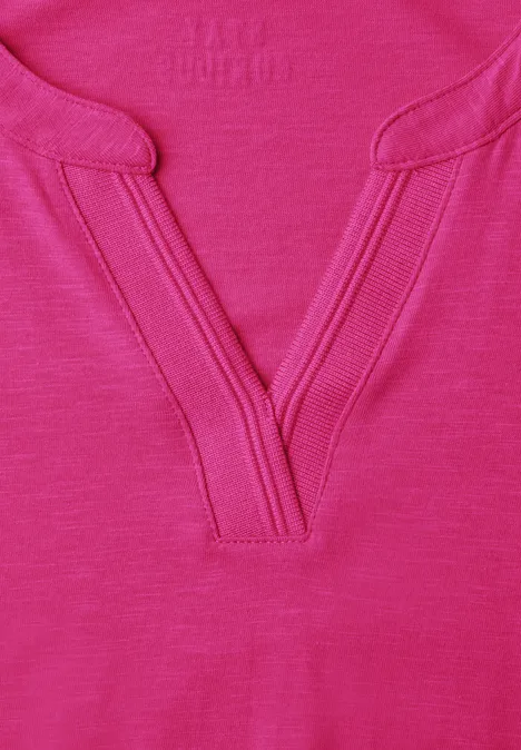 Shirt met split in de hals, in tuniekstijl pink flash Close-up van een felroze T-shirt met V-hals en decoratieve stiksels.
