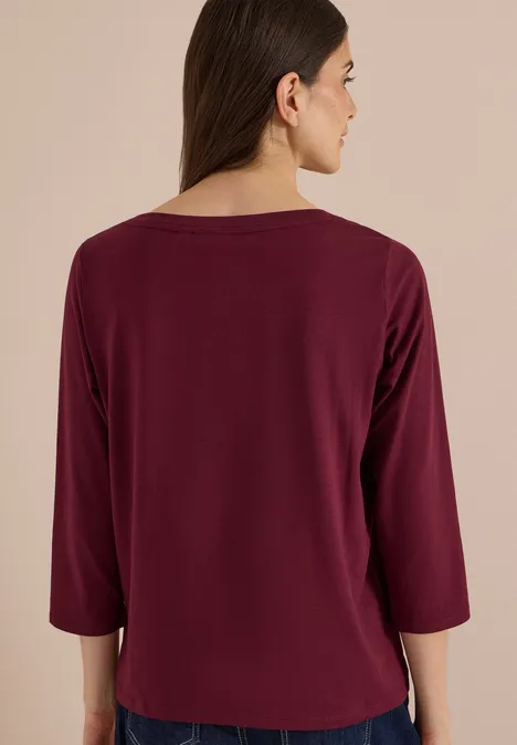Rückansicht einer Frau im weinroten 3/4-Ärmel-Shirt
