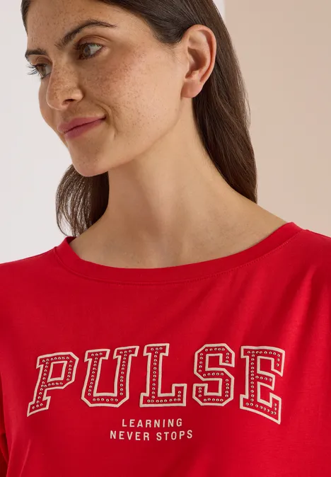 Frau in rotem T-Shirt mit Aufschrift 'PULSE Learning never stops', Nahaufnahme, Blick seitlich
