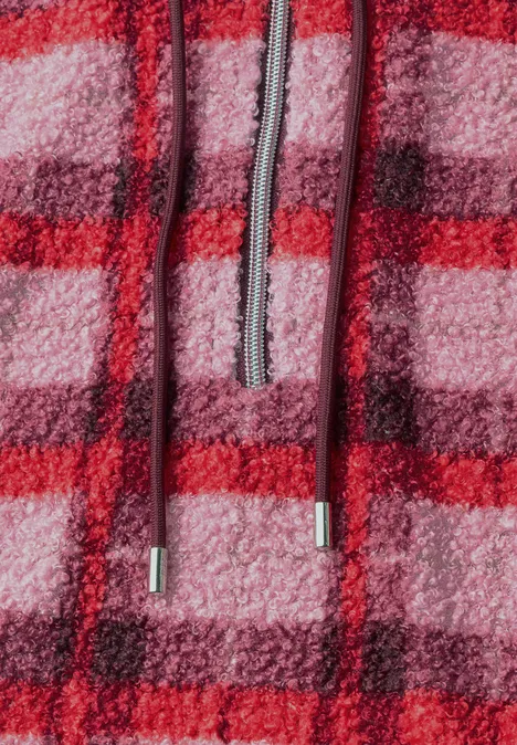 Close-up van een rood-roze geruite fleece hoodie met capuchon en trekkoorden.