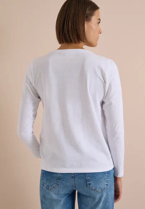 Frau von hinten in weißem Langarmshirt und blauen Jeans