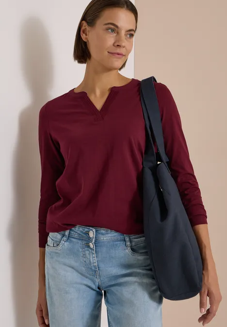 Langarm Shirt im Tunika-Look red wine Eine Frau mit braunem Haar trägt ein bordeauxrotes Langarmshirt und eine Jeans, sie hält eine blaue Tasche.
