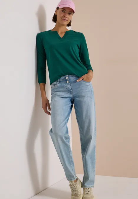 Langarm Shirt im Tunika-Look dark fir green Frau im grünen Langarmshirt, hellblauen Jeans und rosa Cap vor hellem Hintergrund