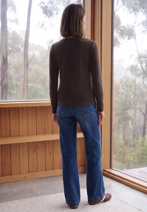 Langarm Shirt mit Tunnelzug am Saum truffle brown Eine Person steht in blauer Jeans und grauem Pullover vor einem großen Fenster und blickt in den Wald.