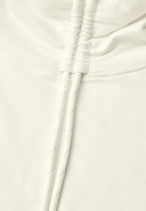 Close-up van een lichtkleurige hoodie met trekkoorden en zachte stof.