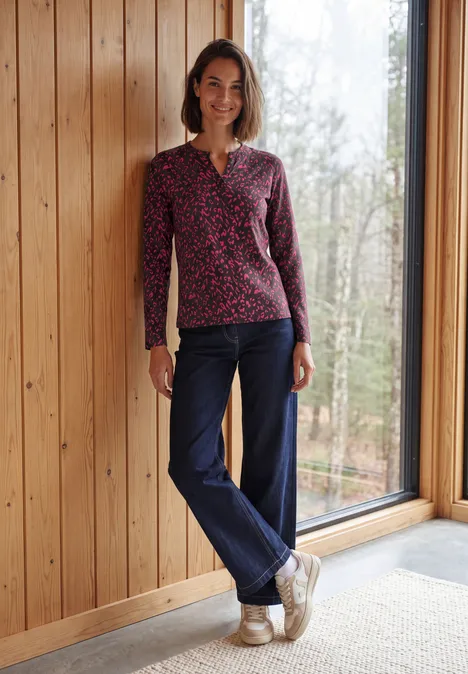 Shirt met split in de hals, in tuniekstijl truffle brown Vrouw lachtend in spijkerbroek en gebreide trui bij raam, houten wand en bos op de achtergrond.
