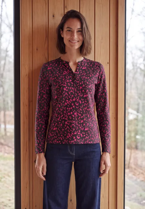 Shirt met split in de hals, in tuniekstijl truffle brown Een vrouw lacht en draagt een donkergekleurd overhemd met lange mouwen en een spijkerbroek voor een houten wand.