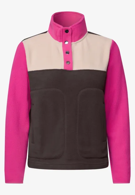 Fleecejacke mit hohem Stehkragen, Knopfleiste, pinken Ärmeln, beigen Schulterpartie und dunkelbraunem Vorderteil.