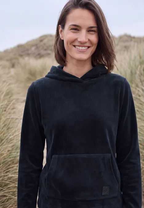 Langarm Shirt aus Cord mit Kapuze urban dark blue Lächelnde Frau in schwarzem Kapuzenpullover vor Dünen und Strandgras.