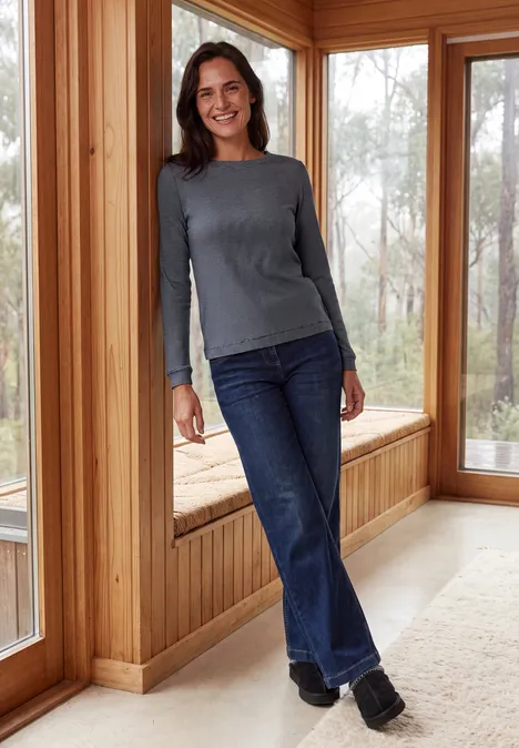 Langarm Shirt mit schmalem Streifenmuster urban dark blue Eine lächelnde Frau in grauem Langarmshirt und Jeans lehnt entspannt am Holzfenster in einem hellen Raum.