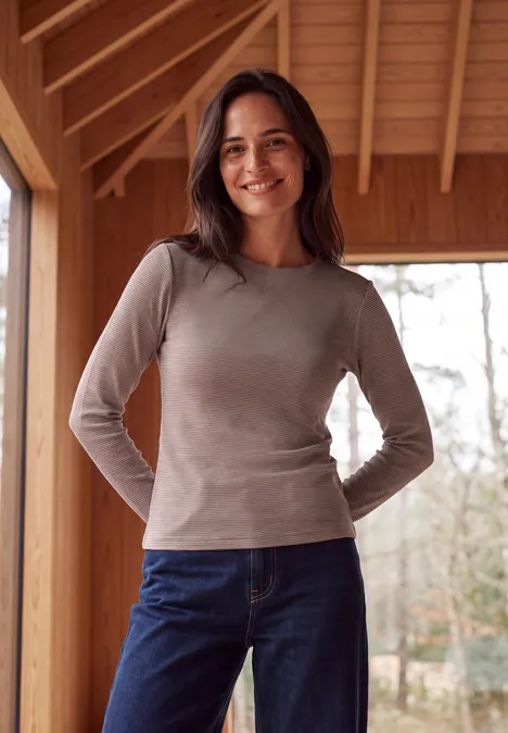 Langarm Shirt mit schmalem Streifenmuster mocha brown Eine lächelnde Frau in grauem Shirt und Jeans steht vor einer Holzwand mit Blick ins Freie.