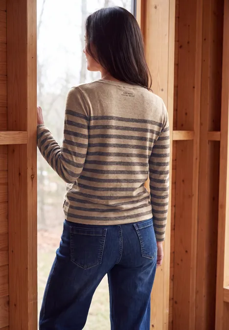 Rückansicht einer Frau in hellem, gestreiftem Pullover und blauen Jeans in einem unfertigen Holzrahmen.