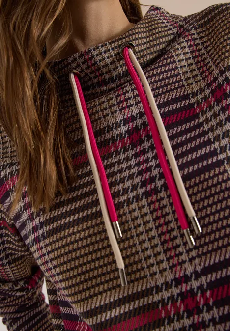 Close-up van een pied-de-poule hoodie met roze trekkoorden en een tailleband.
