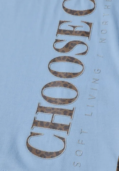 Gros plan d'un vêtement bleu clair avec l'inscription 'CHOOSE' aux grandes lettres à motif.
