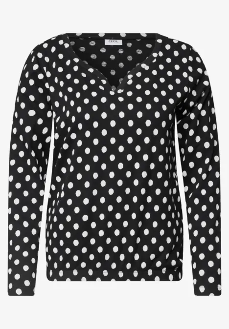 T-shirt à manches longues noir à pois blancs avec col en V.