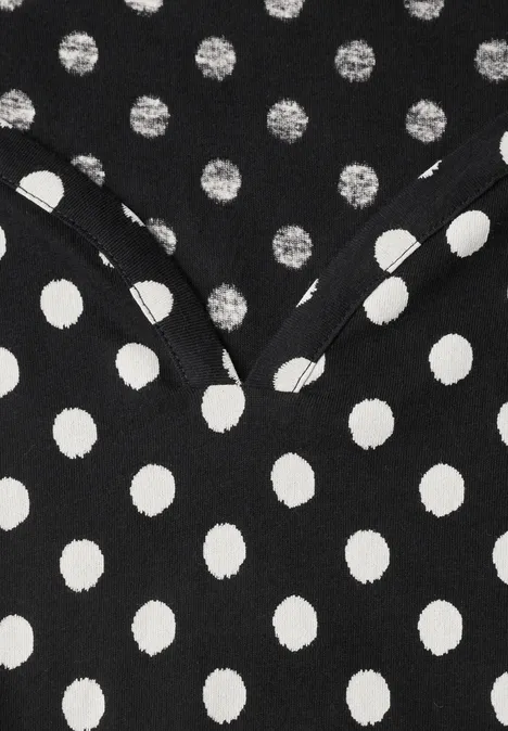 Tissu noir à pois blancs avec couture en V, évoque un vêtement.
