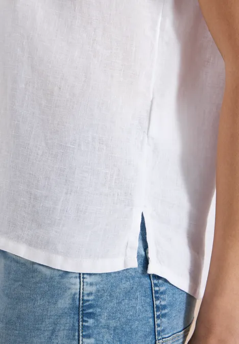 Witte linnen top met zijsplit, gecombineerd met blauw spijkerbroek.