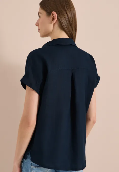 Ein Modell trägt eine dunkelblaue Kurzarmbluse, Ansicht von hinten.