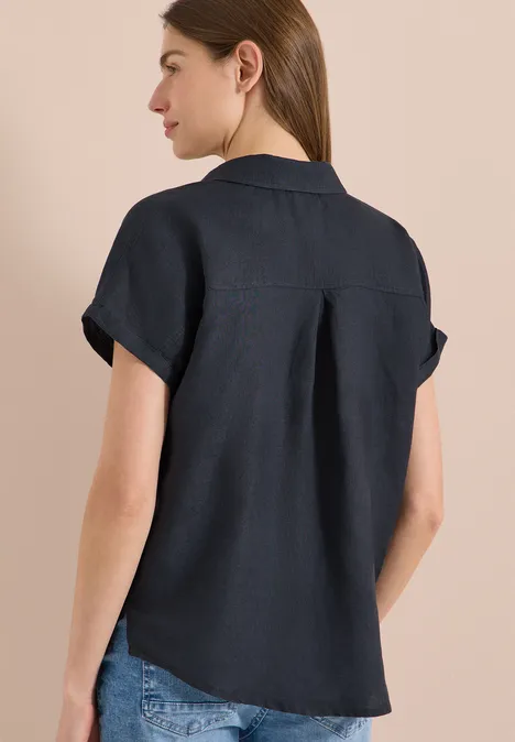 Vrouw van achteren in donkerblauw linnen overhemd met korte mouwen en spijkerbroek