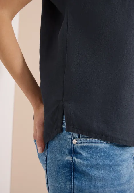 Close-up van iemand met een zwart topje en blauwe jeans, hand lichtjes in de zak.