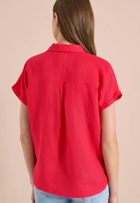 Vrouw van achteren in een rode blouse met korte omgeslagen mouwen en kraag