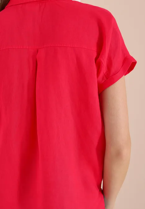 Achteraanzicht van een persoon in een rode blouse met korte mouwen van licht materiaal.