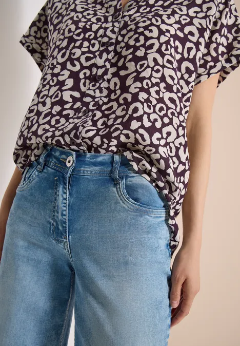 Luipaardprint-shirt en blauwe jeans, torso-opname.