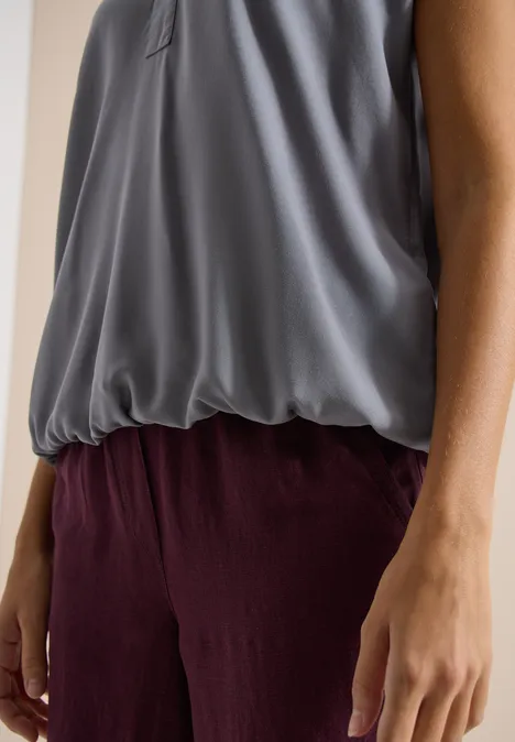 Blouse met korte mouwen en gespleten hals graphite light grey Grijs vallend hemdje gecombineerd met een losvallende bordeauxrode broek, zijdelingse weergave van torso en armen.