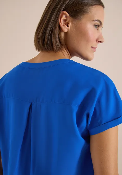 Blouse met korte mouwen en gespleten hals surf blue Vrouw van achteren met halflang haar draagt een felblauw kortärmelig shirt.