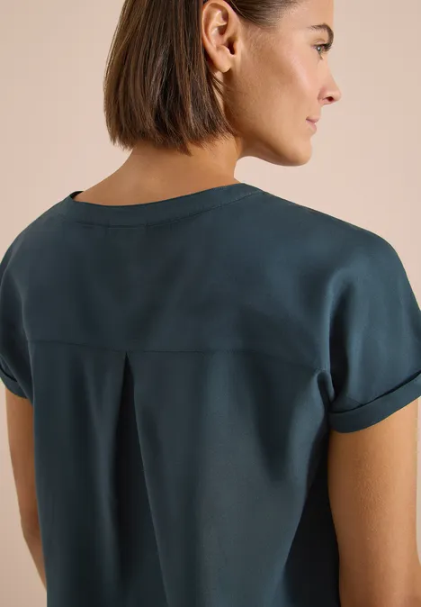 Kurzarm Bluse mit Split Neck deep petrol blue Frau von hinten in dunkelblauer Kurzarmbluse mit umgeschlagenen Ärmeln und sichtbarem Nacken.
