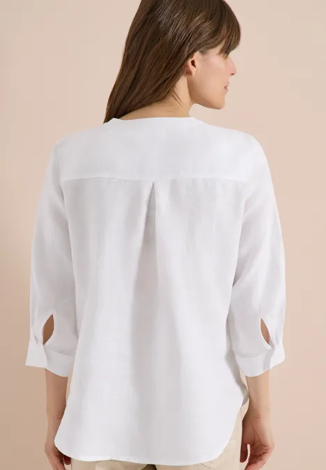 3/4-Arm Tunika aus reinem Leinen White Frau von hinten in weißer Bluse mit Mittelfalte, dreiviertel Ärmeln und abgerundetem Saum.