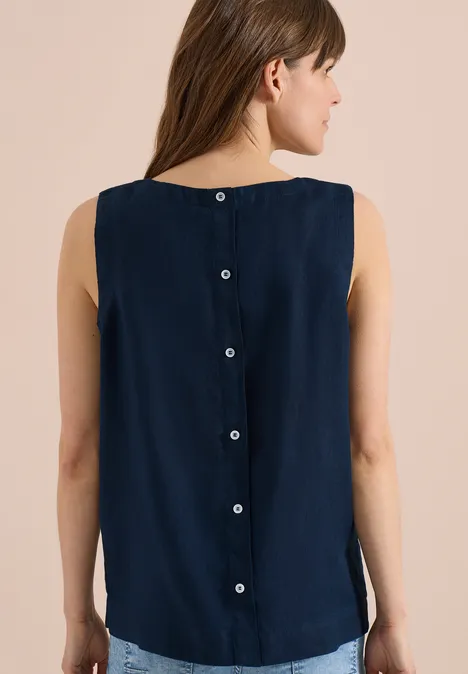 Frau von hinten in dunkelblauer ärmelloser Bluse mit zentraler Knopfleiste.