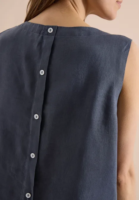 Rückenansicht einer Frau in ärmellosem, dunkelblauem Leinenoberteil mit Knopfleiste hinten.