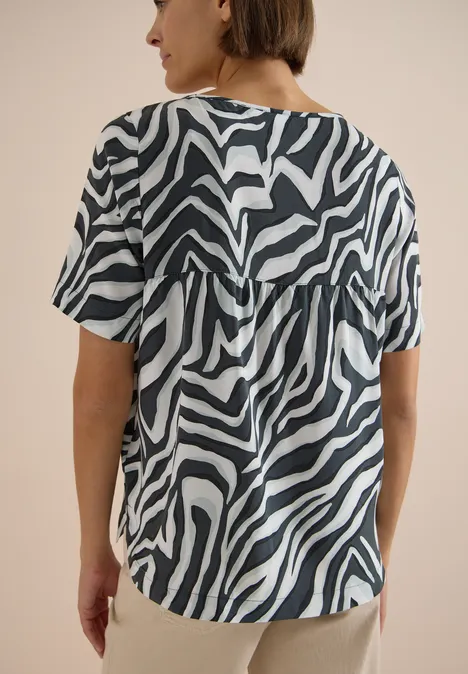 Frau von hinten in kurzärmligem Shirt mit schwarz-weißem Zebramuster.
