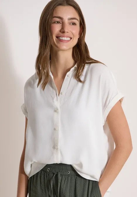 Kurzarm Hemdbluse in Unifarbe vanilla white Person trägt locker sitzende weiße Bluse mit kurzen Ärmeln, eine Hand in der Hosentasche.