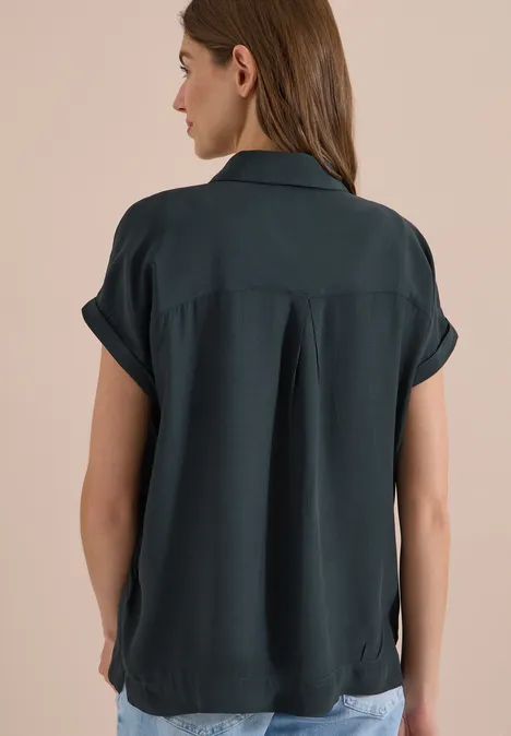 Kurzarm Hemdbluse in Unifarbe palm breeze green Rückenansicht einer Frau in dunkelgrüner kurzärmeliger Bluse mit Kragen vor schlichtem beigem Hintergrund.