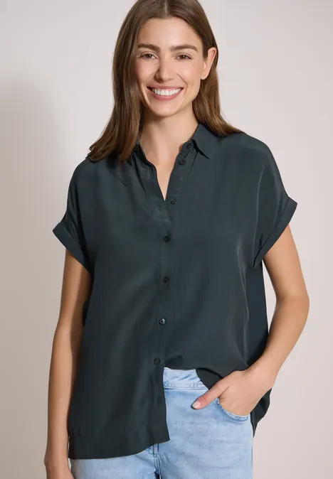 Kurzarm Hemdbluse in Unifarbe palm breeze green Eine Frau trägt eine dunkelblaues, kurzärmeliges Hemd mit Knopfleiste und helle Jeanshose.