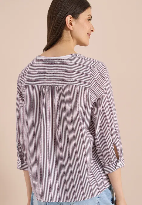 Achteraanzicht van persoon met gestreept overhemd en opgerolde mouwen.