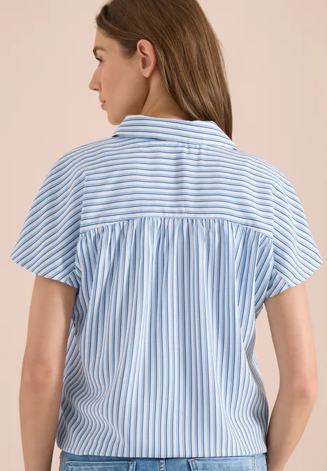 Vrouw van achteren in blauw-wit gestreept kort overhemd met rugpas en plooien