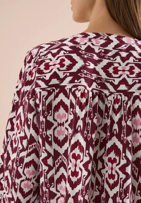 Achteraanzicht van een vloeiende blouse met bordeaux-witte ikatprint.