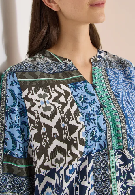 Close-up van een vrouw in een blauw-groen patroon blouse.