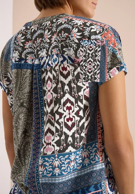 Femme de dos portant un haut patchwork multicolore à motifs floraux et géométriques.