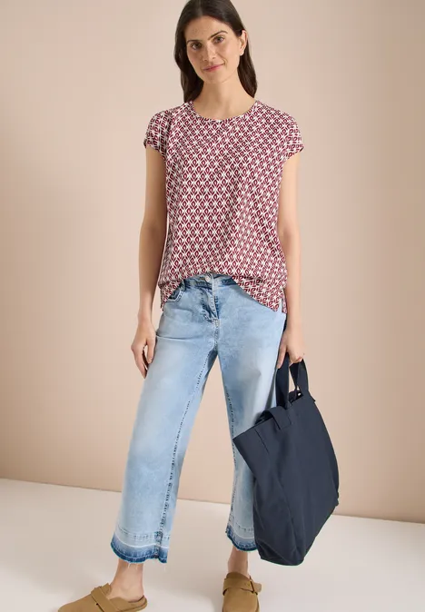 Femme en t-shirt à pois, jean ample et sac fourre-tout bleu marine à la main.