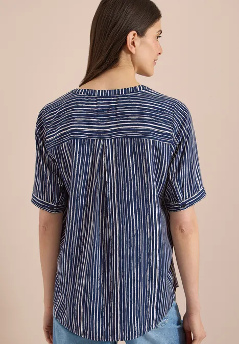 Achteraanzicht van een vrouw in een blauw-wit gestreept kort mouw blouse voor een lichte achtergrond.